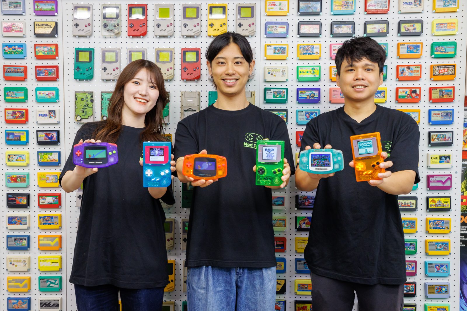 Three Mod Tokyo staff smiling and holding up freshly built Game Boys