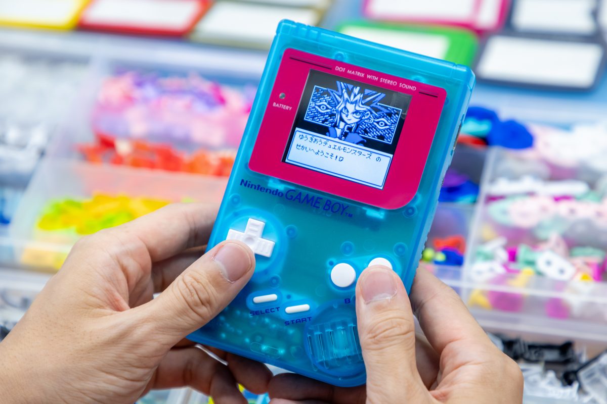 Coral-red Game Boy with teal buttons, screen lit