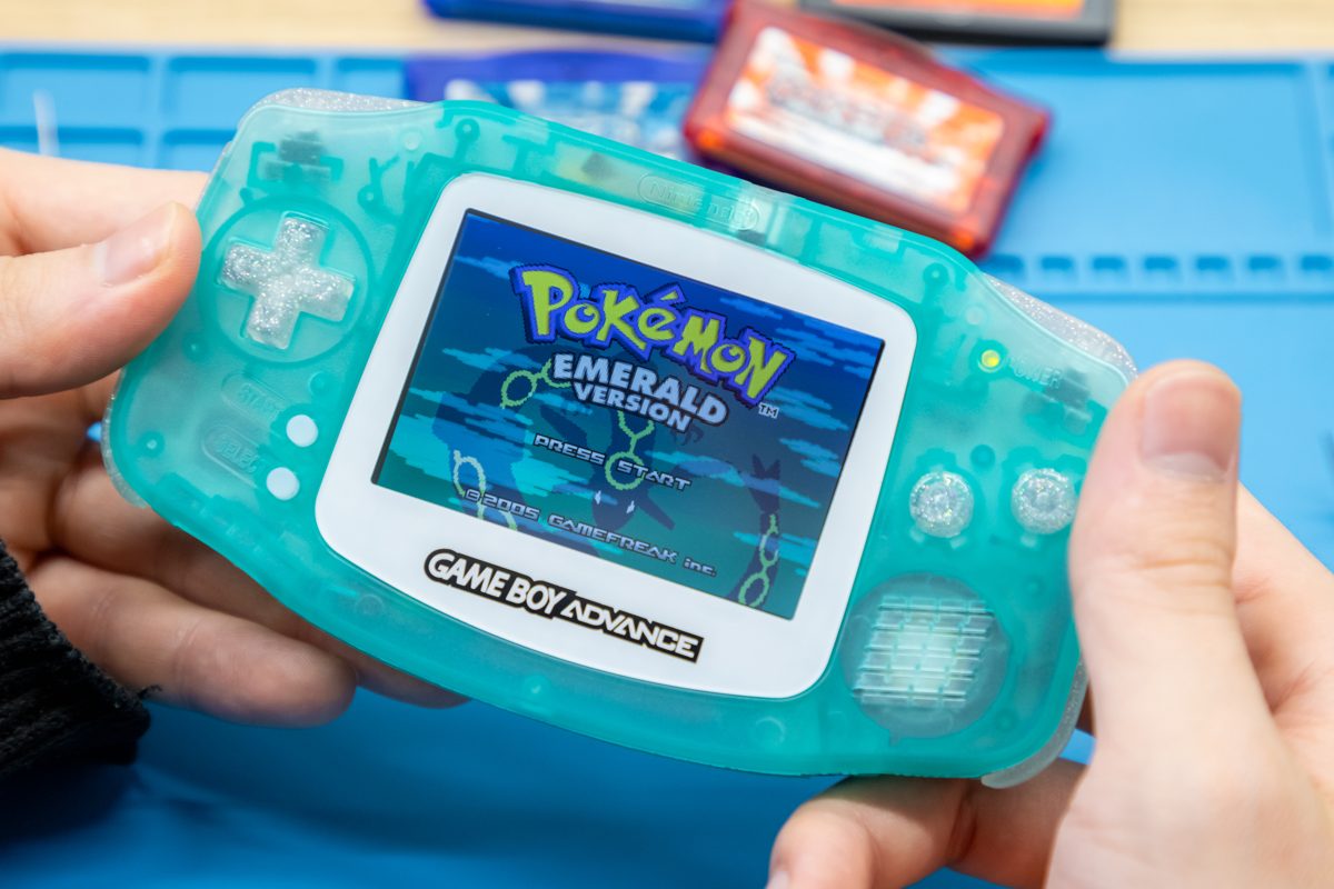 Teal Game Boy Advance playing Pokémon, screen lit