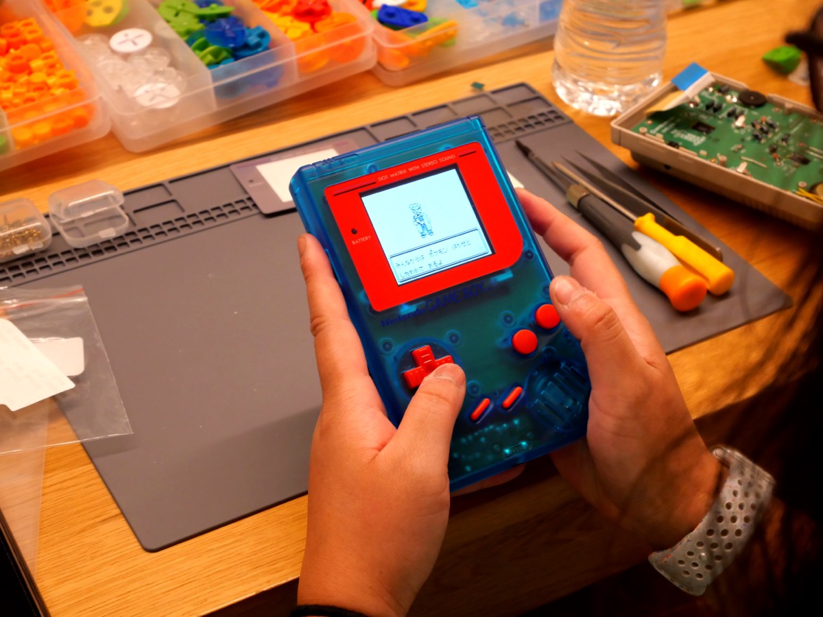Clear-blue Game Boy with red buttons, screen lit