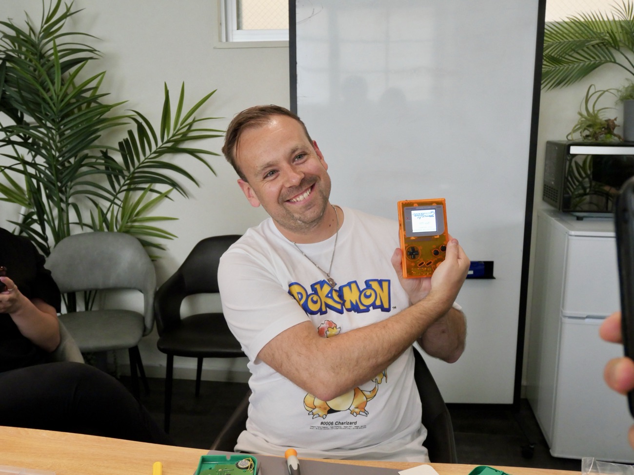Guest in a Pokémon shirt grinning with his orange Game Boy