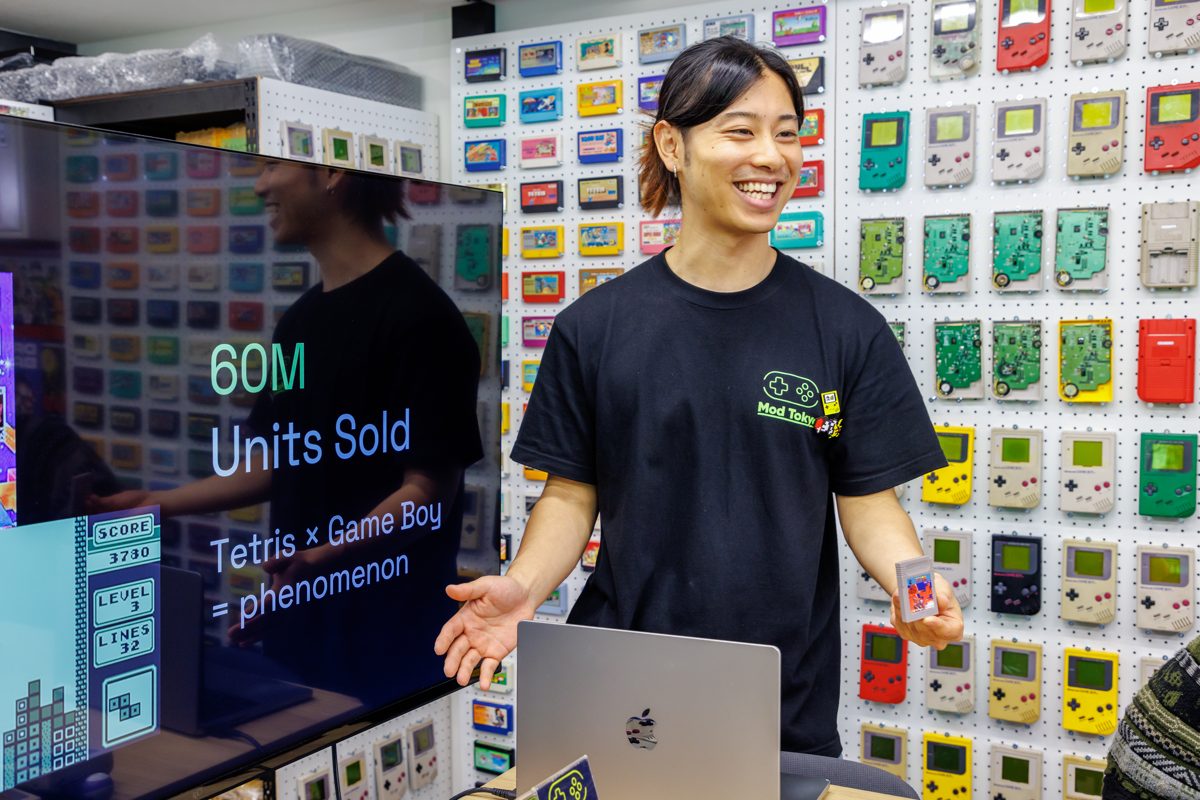 Guide welcoming participants in front of the Game Boy history slide